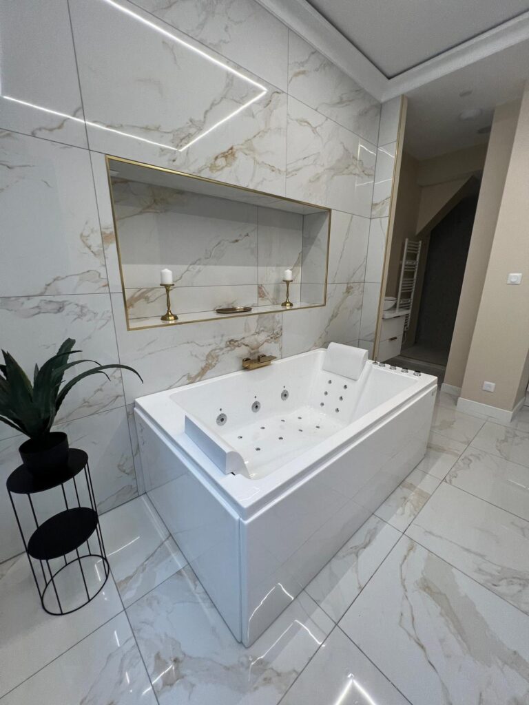 Espace bain finalisé avec baignoire balnéo, niche murale et carrelage effet marbre dans un appartement haut de gamme à Rouen.