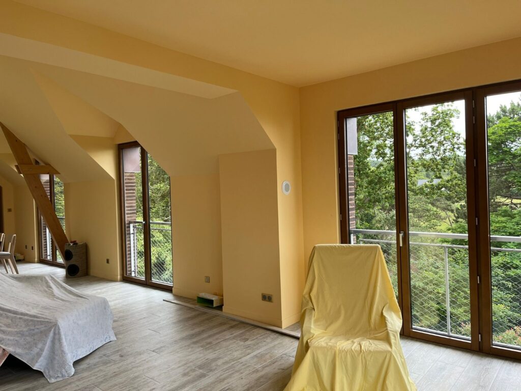Grande pièce rénovée avec peintures intérieures claires, baies vitrées et vue dégagée dans une maison à Rouen.