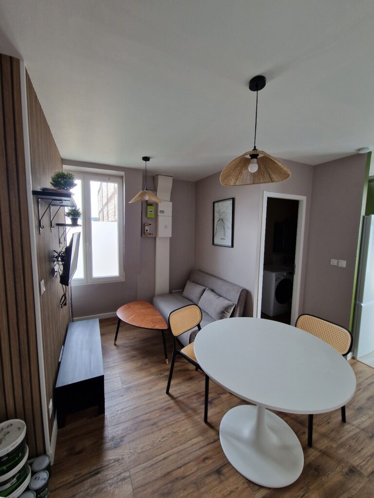 Séjour rénové avec tasseaux muraux, table ronde et aménagement intérieur contemporain dans un appartement à Rouen.